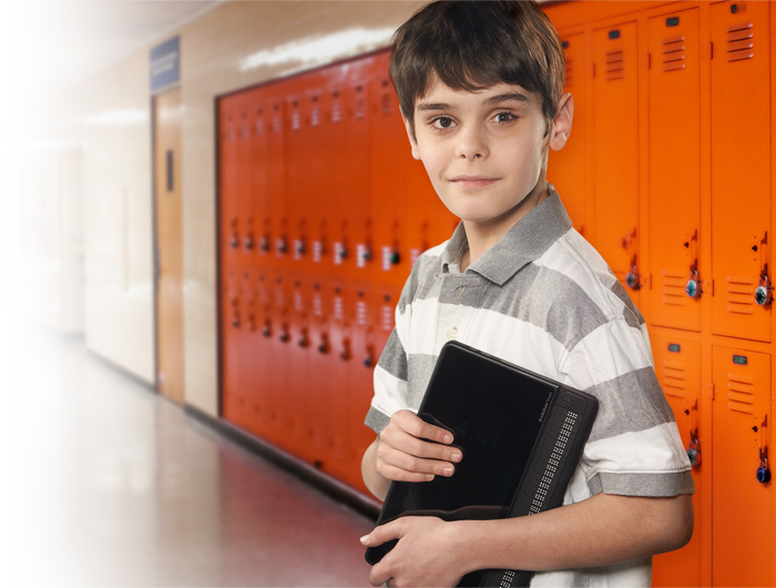 Photo d'un garçon dans un couloir d'école avec son BrailleNote Touch en main