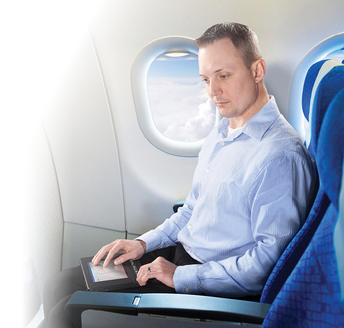 Photo montrant un homme qui utilise le BrailleNote Touch à bord d'un avion