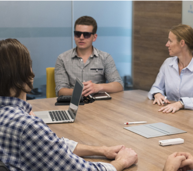 A young professional with colleagues sitting at a meeting room table.