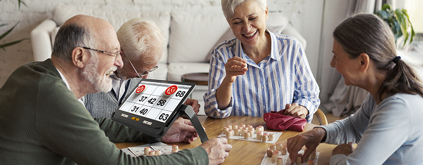 Un groupe de personnes âgées jouant au bingo avec l'une des personnes utilisant la loupe électronique explore 12 pour voir les numéros plus clairement pendant le jeu. 