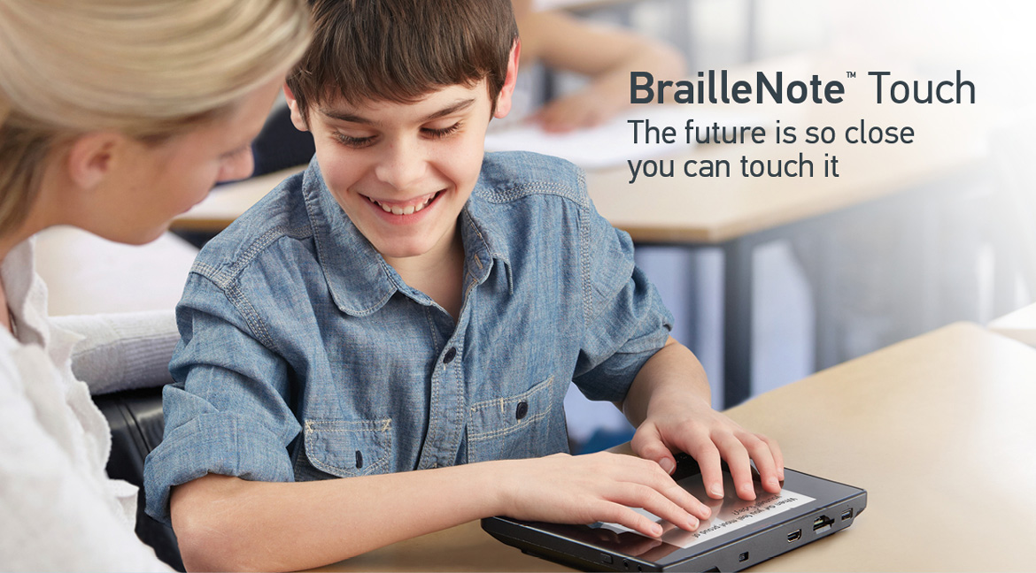 Image showing a school boy typing on the touch screen of the BrailleNote Touch and his teacher following on the screen – BrailleNote Touch: The future is so close you can touch it.