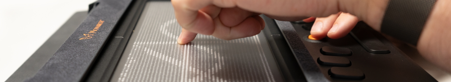 A hand touch’s the Monarch tactile array which is displaying a tactile graphic