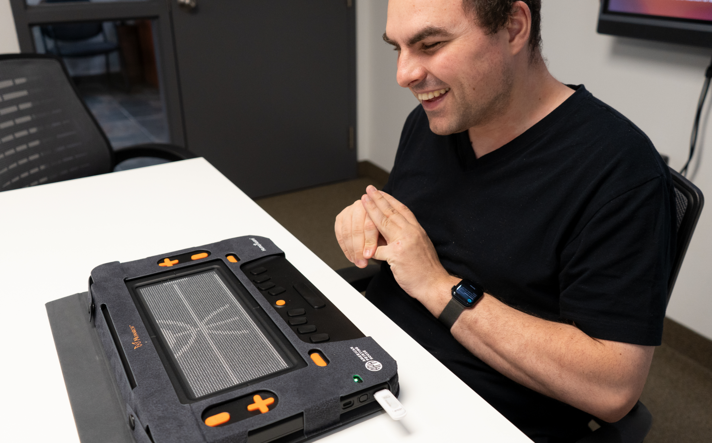 A smiling person in front of the Monarch. The touch screen displays the outline of a character