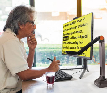 Image of a man reading text on his computer, displaying black text on a bright yellow background, creating a strong contrast.