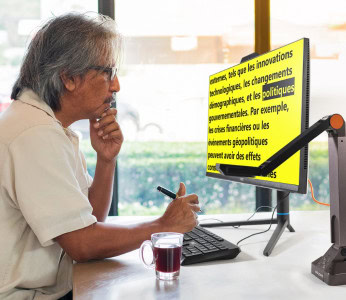 Image d’un homme lisant du texte sur son ordinateur, présentant du texte noir sur un fond jaune vif, créant un fort contraste.