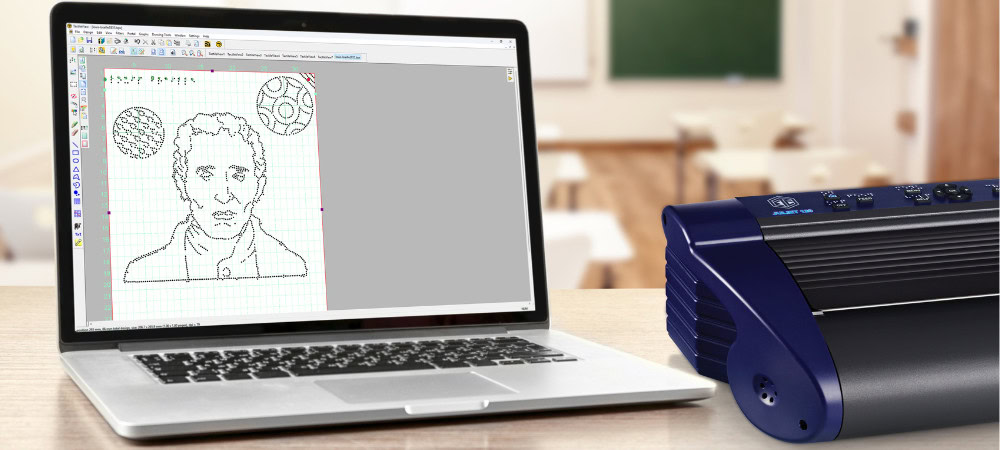 Image of a laptop displaying a dashed drawing, next to a Braille embosser.
