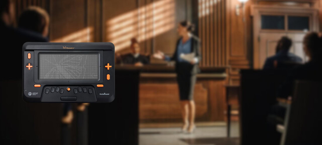Image of a Monarch tactile tablet displayed prominently in the foreground, with a blurred courtroom scene in the background where a lawyer presents a case before a judge.