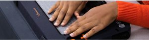 Hand of a person wearing an orange sweater reading with the Monarch.