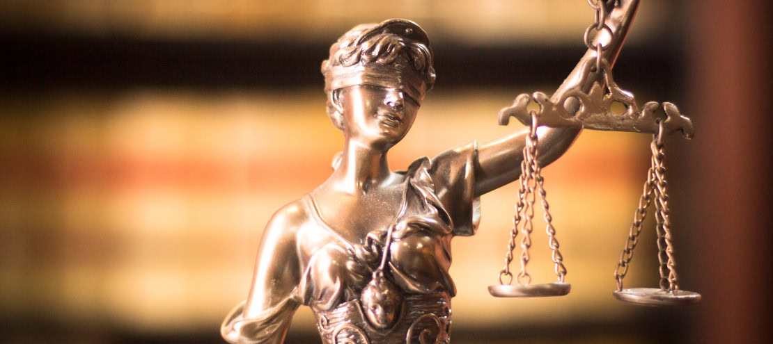 Bronze statue of Lady Justice holding scales, symbolizing fairness and the law.