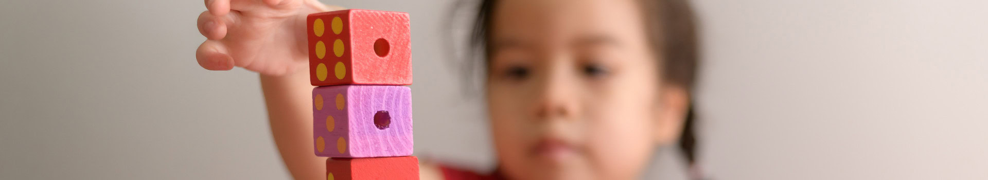 Close-up of a child stacking colorful wooden blocks, focused on the activity.