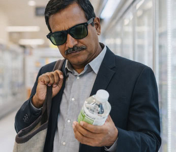 Man wearing Ray-Ban Meta glasses reads a bottle label in a store.