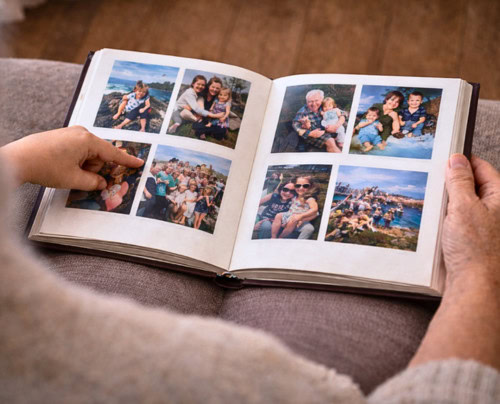 Close-up of an open photo album with a hand pointing at a picture. Close-up of an open photo album with a hand pointing at a picture.