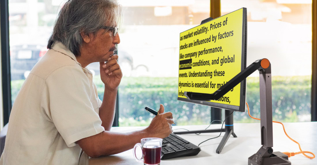 Man reading enlarged text on a monitor with a desk camera. Man reading enlarged text on a monitor with a desk camera.