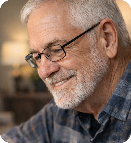 Close-up of an older man smiling, wearing glasses.