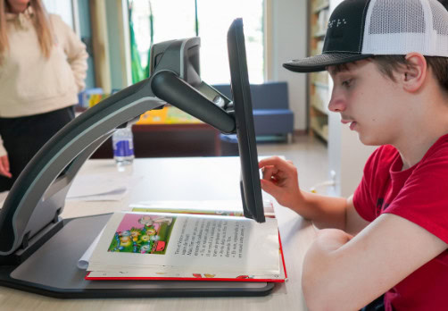 Young student reading a book with a Reveal 16.