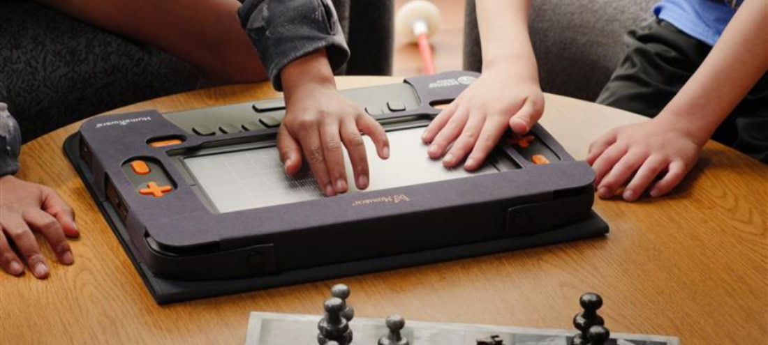 Enfants découvrant le jeu d’échecs avec un afficheur braille Monarch.