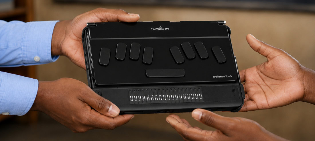 BrailleNote Touch being passed to a user, illustrating the impact of assistive technology donations.
