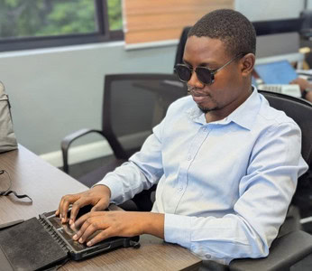 Erick using a BrailleNote device to study, read, and take notes independently.