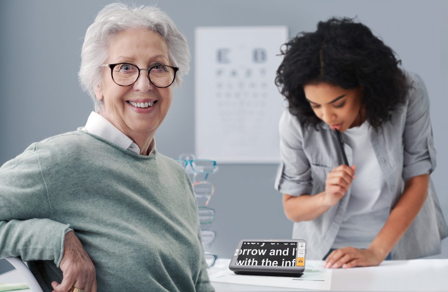 A smiling elderly woman sits in an optician's office. l' exploré 5 is on the table.